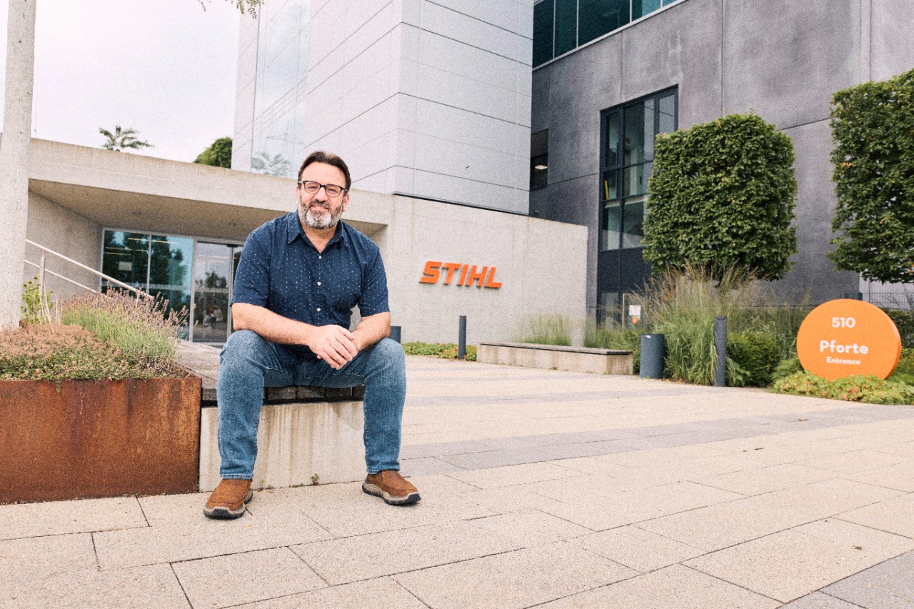 Scott Smith sitzt vor einem STIHL Gebäude